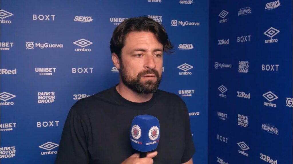 Rangers manager Russell Martin speaking to RangersTV during a media interview in front of the club sponsor wall at Ibrox