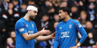 Robin Propper (left) wearing a head bandage speaks to teammate Jefte during a Rangers match.