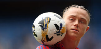 Thelo Aasgaard balances a Puma match ball on his shoulder while wearing a red and blue Rangers warm-up top during a pre-season friendly against Club Brugge