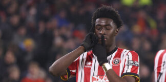 Sheffield Unite's Jesurun Rak-Sakyi celebrates with a shushing gesture during a match against Middlesbrough in the Sky Bet Championship, wearing red and white stripes.