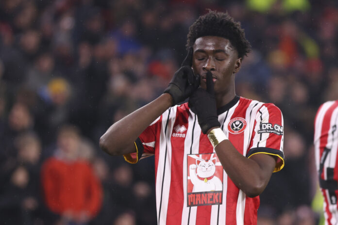 Sheffield Unite's Jesurun Rak-Sakyi celebrates with a shushing gesture during a match against Middlesbrough in the Sky Bet Championship, wearing red and white stripes.