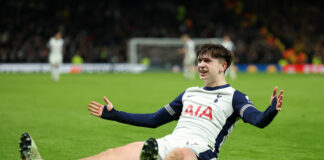 Tottenham Hotspur player Mikey Moore slides on his knees in celebration on the pitch during a UEFA Europa League match.