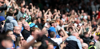 Ex-Rangers Coach Harry Watling Set for Premier League Move with Wolves Rangers fans celebrate passionately in the stands during an Old Firm clash against Celtic.