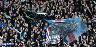 Rangers supporters waving large flags and cheering during a match against Viktoria Plzen in the UEFA Champions League qualifiers.
