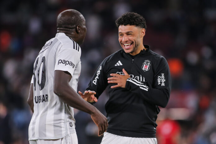 Alex Oxlade Chamberlain smiling in Besiktas training gear while talking with a teammate during warm up