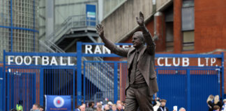 Statue of former Rangers manager Walter Smith outside Ibrox Stadium surrounded by supporters paying tribute.