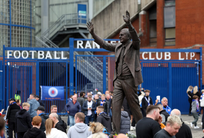 Statue of former Rangers manager Walter Smith outside Ibrox Stadium surrounded by supporters paying tribute.