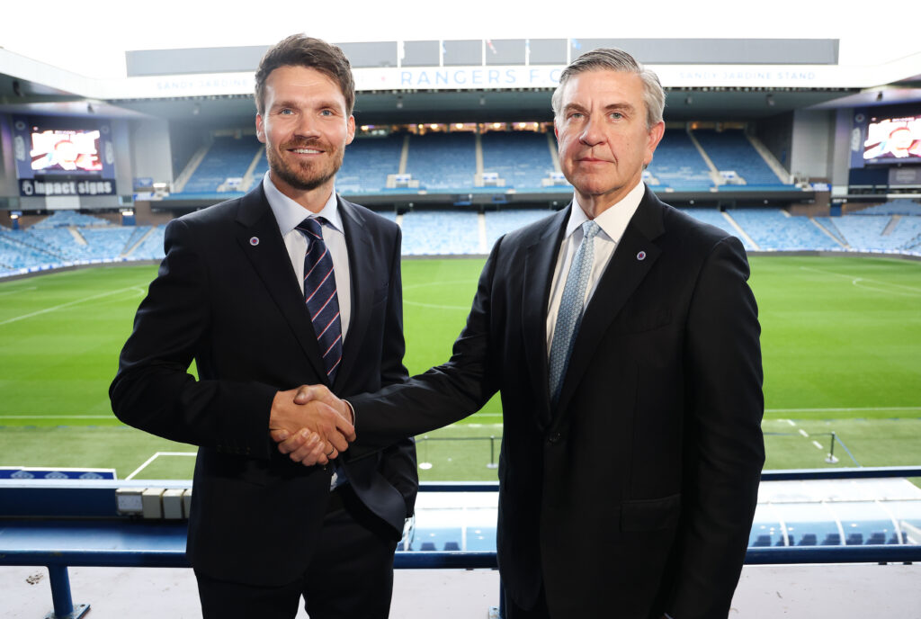 Danny Röhl stands with Andrew Cavenagh at Ibrox as they shake hands in front of the pitch during his Rangers unveiling