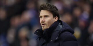Danny Rohl standing on the touchline wearing a dark padded jacket during a Scottish Premiership match at Ibrox.