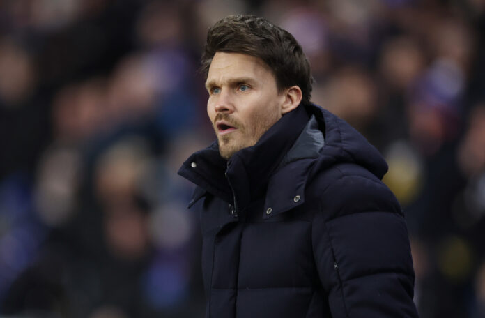 Danny Rohl standing on the touchline wearing a dark padded jacket during a Scottish Premiership match at Ibrox.