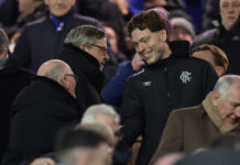 Andreas Skov Olsen smiling and shaking hands with Rangers officials in the Ibrox stands before kick off