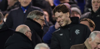 Andreas Skov Olsen smiling and shaking hands with Rangers officials in the Ibrox stands before kick off