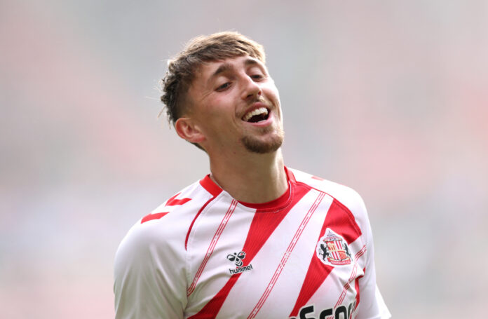 Dan Neil in action for Sunderland during a Premier League match, wearing the club's red and white home kit