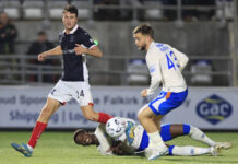 Emmanuel Fernandez lies on the turf at Falkirk as Rangers fans rage.
